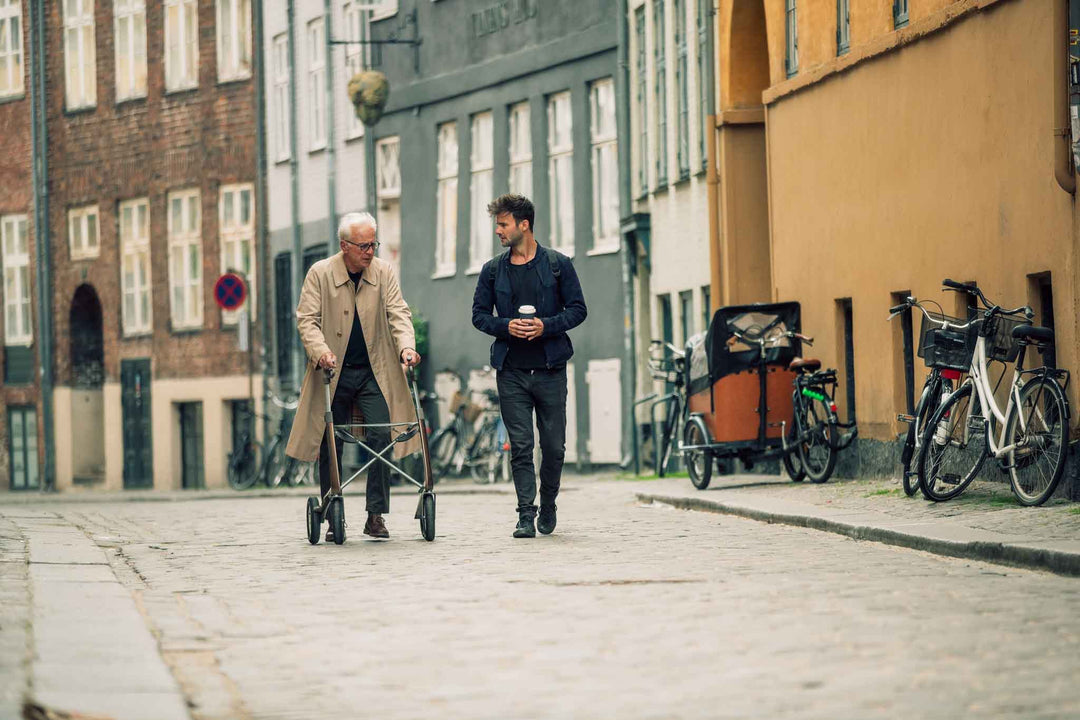 A man walks with a carbon fibre 'byACRE Overland' walking frame along a street in Copenhagen with his friend.