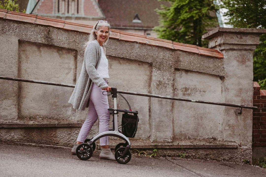 A woman walks downhill using a saljol walker rollator