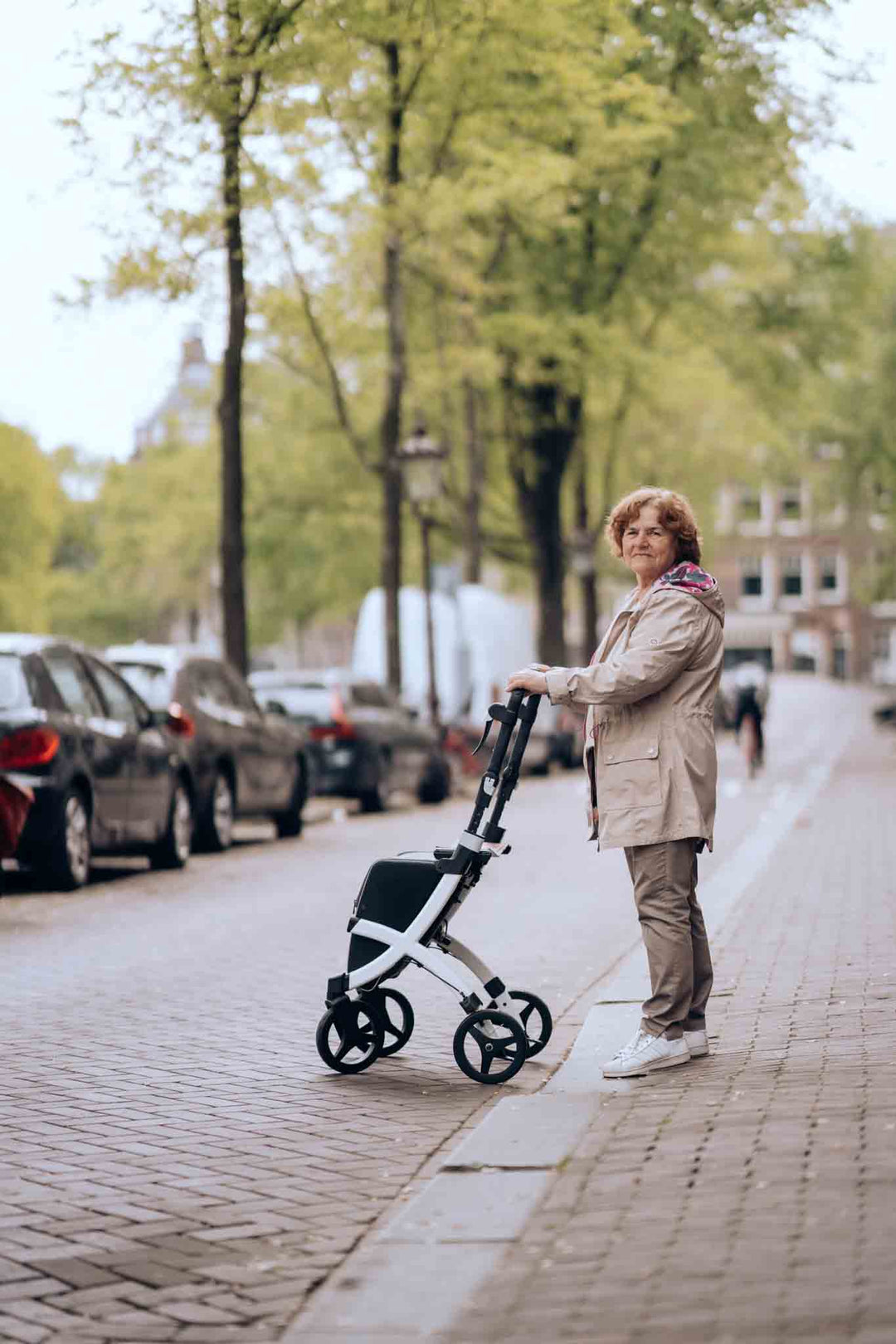 A woman stands on a brick lane with the 'Rollz Flex' walking frame