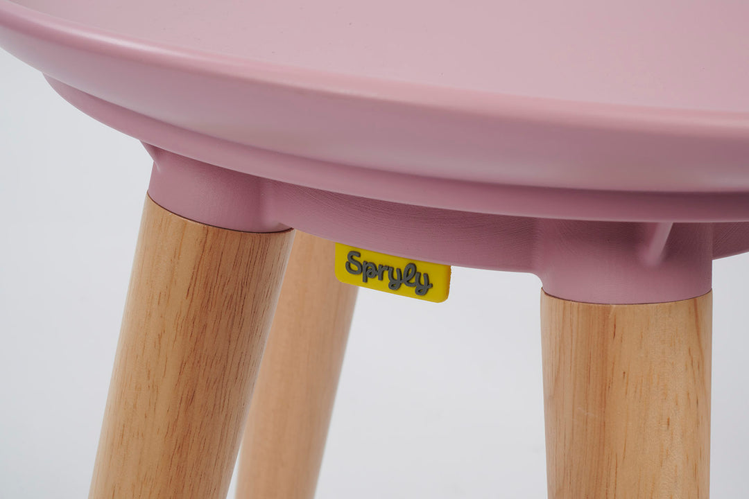 Pink stool with wooden legs and Spryly logo on a white background