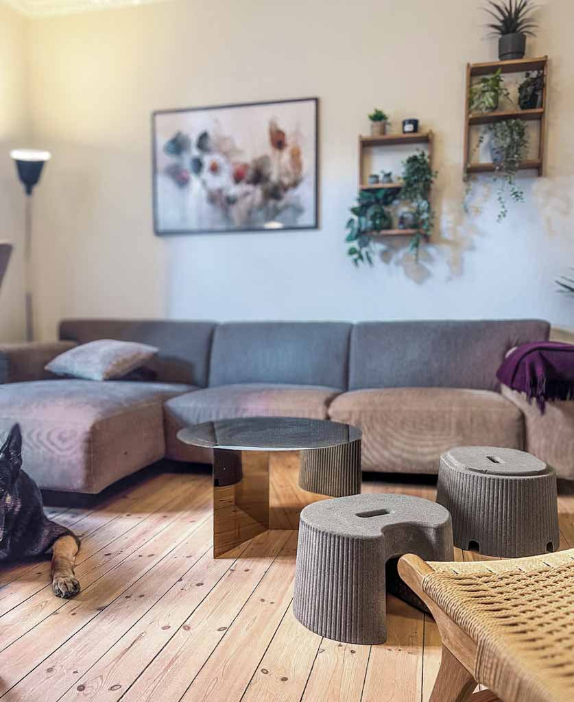 Modern living room with a grey sectional sofa, decorative coffee table, and wall art and two foot supports
