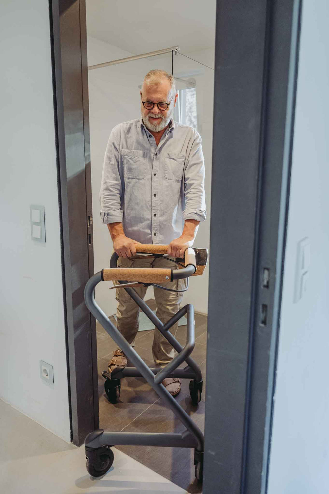 A man navigates through a tight bathroon door using a Saljol Indoor Walker for support