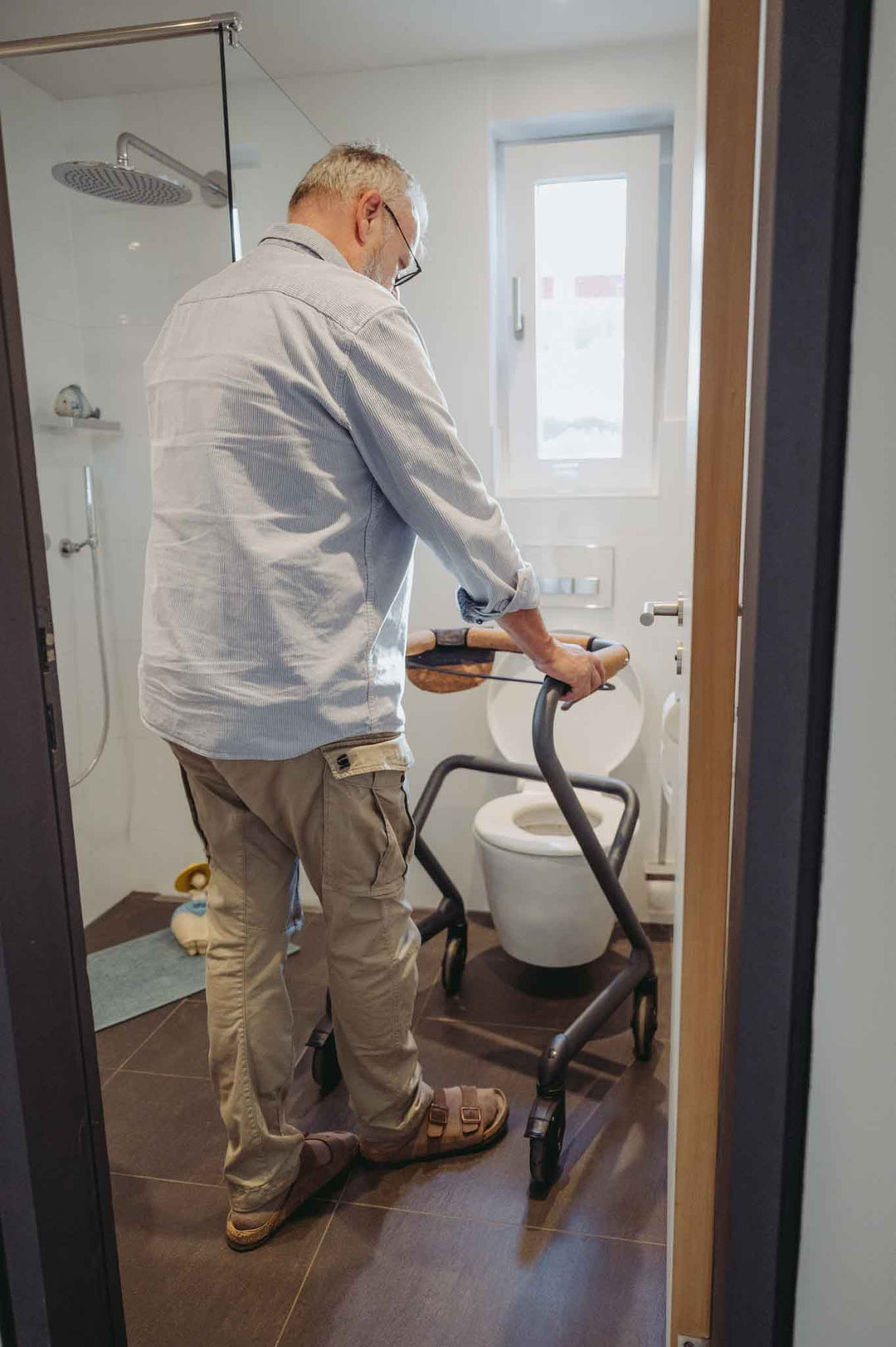 Man using a mobility scooter in a bathroom with a toilet and shower