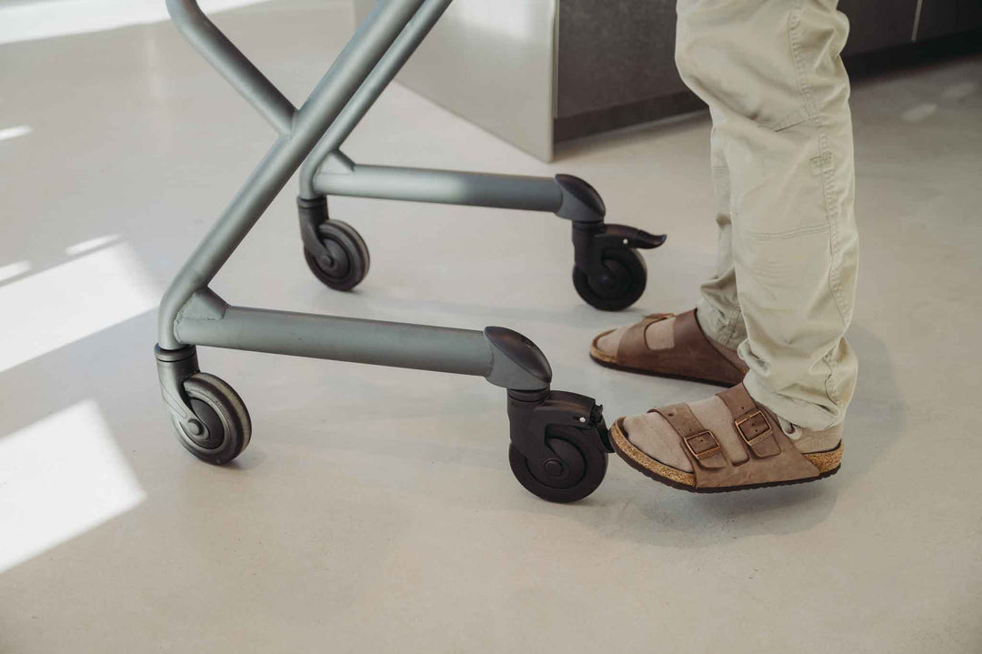 Person wearing sandals adjusting the direction brake sytem on a indoor mobility walker