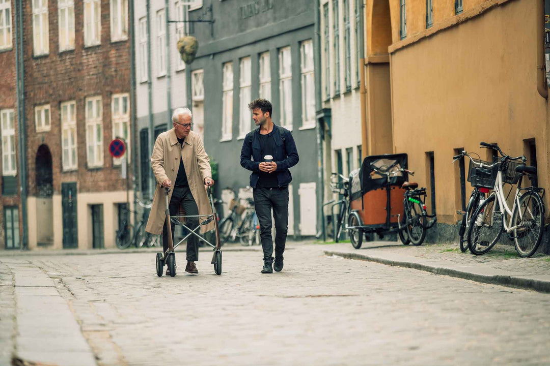 A man walks with a carbon fibre 'byACRE Overland' walking frame along a street in Copenhagen with his friend. 