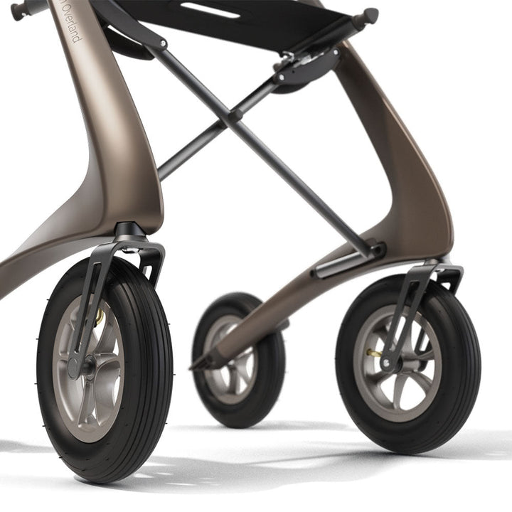 Close up of a front wheels on a brown 'byACRE Carbon Overland' rollator, on a white background.